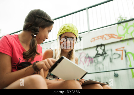 Mädchen sitzen auf Stufen mit Tablet-Computern, Mannheim, Baden-Württemberg, Deutschland Stockfoto