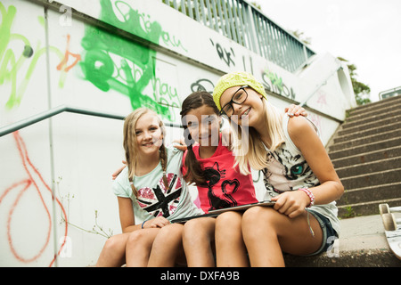 Mädchen sitzen auf Stufen mit Tablet-Computern, Mannheim, Baden-Württemberg, Deutschland Stockfoto