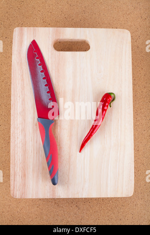 Frische rote Chilischote mit Messer auf Schneidebrett. Stockfoto