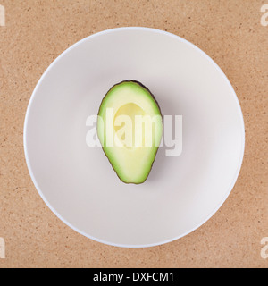 Die Hälfte der Avocado auf Platte, über hölzerne Hintergrund. Stockfoto