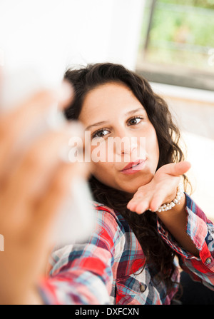 Teenager-Mädchen posieren, weht Küsse und nehmen Selfie mit Smartphone, Deutschland Stockfoto