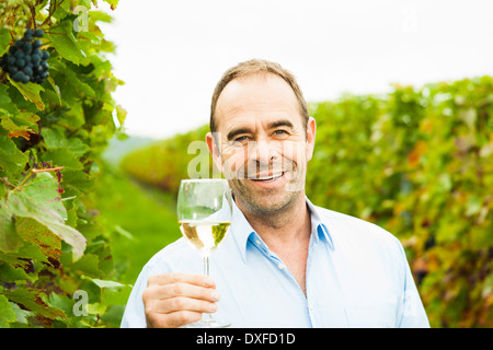 Porträt der Winzer mit Glas Wein im Weinberg, lächelnd und Blick in die Kamera, Rheinland-Pfalz, Deutschland Stockfoto