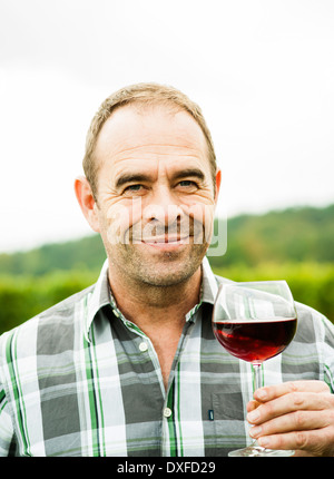 Close-up Portrait des Winzers im Weinberg, mit Glas Wein, lächelnd und Blick in die Kamera, Rheinland-Pfalz, Deutschland Stockfoto