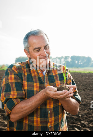 Porträt der Bauer im Feld stehen, halten Sämling Pflanze von Ernte, Deutschland Stockfoto