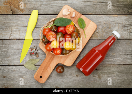 Cherry-Tomaten auf Cutting Board und Ketchup Flasche über Holztisch Hintergrund Stockfoto