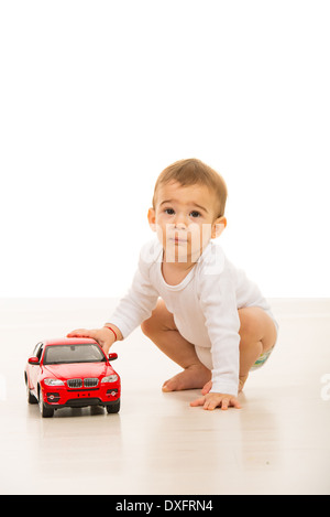 Schöne Baby junge spielt mit einem großen Auto-Spielzeug auf Etage Stockfoto