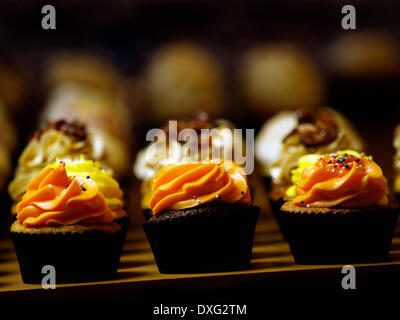 Reihe von sortierten Cupcakes mit orangefarbenen Glasur Stockfoto