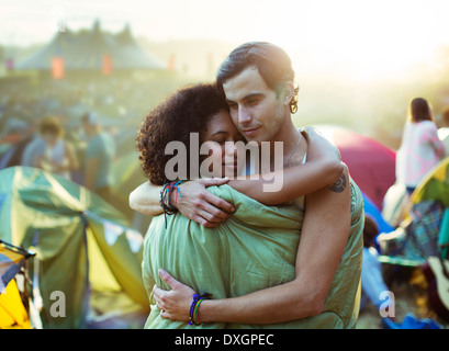 Paar im Schlafsack umarmt draußen Zelte beim Musikfestival Stockfoto