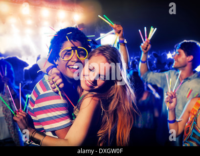 Paar mit Leuchtstäben umarmt beim Musikfestival Stockfoto