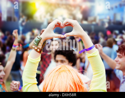 Frau bildet Herzform mit Händen am Musikfestival Stockfoto