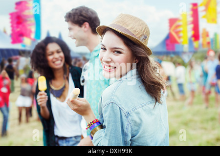 Porträt der Frau Essen aromatisierte Eis mit Freunden beim Musikfestival Stockfoto