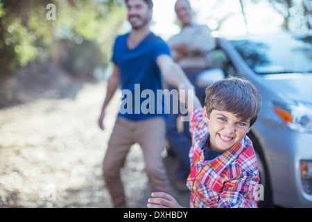 Fröhlicher Junge Vater am Arm außerhalb Auto ziehen Stockfoto