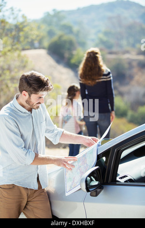 Mutter und Tochter betrachten, während Vater Karte überprüft Stockfoto