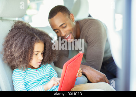 Vater und Tochter mit digital-Tablette auf Rücksitz des Autos Stockfoto