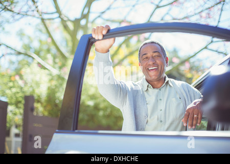 Porträt von senior glücklich stützte sich auf Autotür Stockfoto