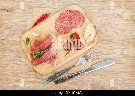 Schinken, Salami, Brot, Gemüse und Gewürze. Über Holztisch Hintergrund Stockfoto