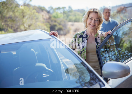 Porträt von glücklich senior Frau stützte sich auf Auto Stockfoto