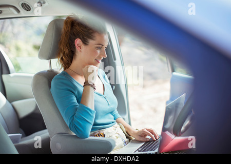 Frau mit Laptop im Auto Stockfoto