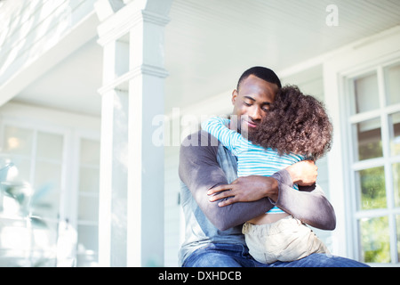 Vater umarmt Tochter auf Veranda Stockfoto