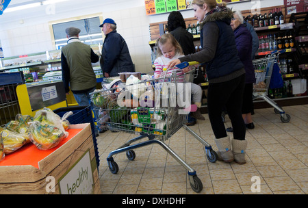 Eine Mutter und ein Kind im Lidl-Supermarkt, die einen vollen Trolley mit Lebensmitteleinkäufen in der Warteschlange stehen Großbritannien KATHY DEWITT Stockfoto