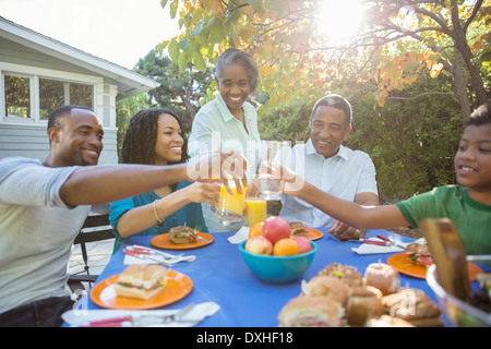 Glückliche Familie Toasten Saft Gläser bei Terrassentisch Stockfoto