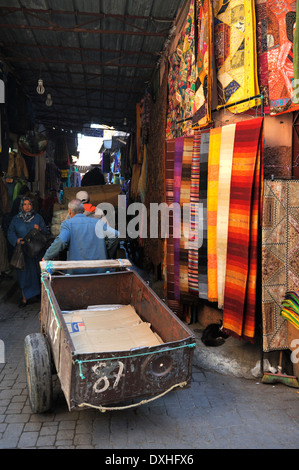Handwagen hinunter schmalen Durchgang im Souk der Djemaa el-Fna Platz, Marrakesch mit Teppichen an Wand Stockfoto