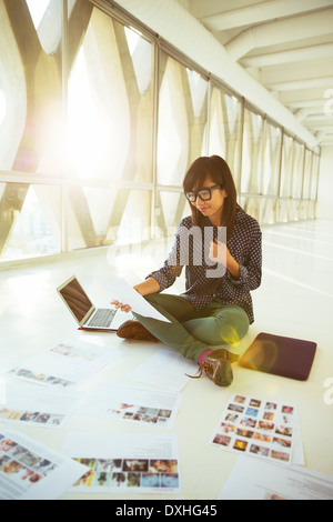 Kreative Geschäftsfrau Blick auf Foto-Beweise auf Büroetage Stockfoto