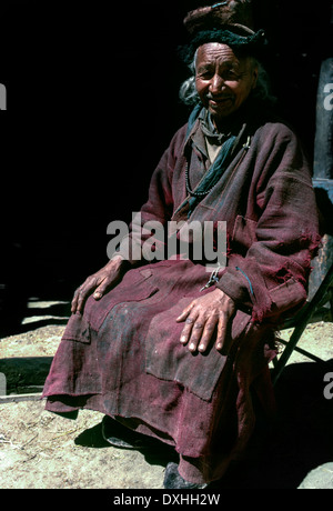 Ladakh, die alten Mann sitzen Stuhl Hände auf Knien lächelnd schwarzer Schatten Hintergrund Sonnenschein traditionelle Gonca gepatcht wird empfohlen Stockfoto