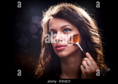 Junge Frau entfernen überschüssige Pulver mit Fächerpinsel Stockfoto