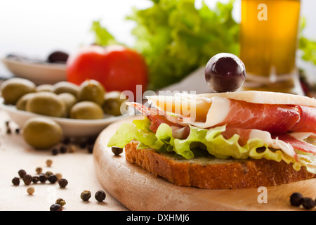 Schinken und Käse-Sandwich mit Oliven und Salat. Schwerpunkt liegt auf den Käse. Geringe Schärfentiefe. Stockfoto