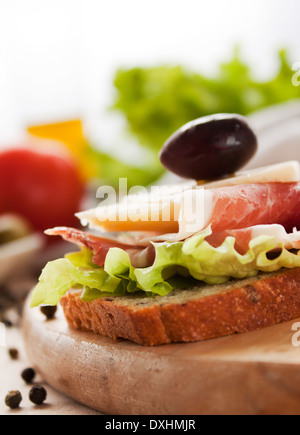 Schinken und Käse-Sandwich mit Oliven und Salat. Stockfoto