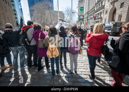 Touristen aller cluster und posieren für Fotos vor der Wall Street Bull am Broadway in Lower Manhattan in New York Stockfoto