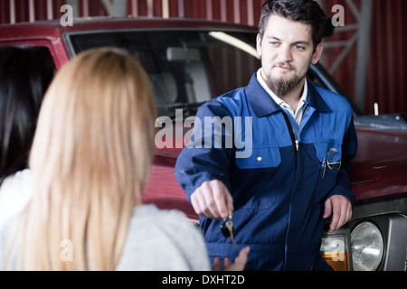Schöne Auto Mecanic die Schlüssel an dem Client zurückzugeben Stockfoto