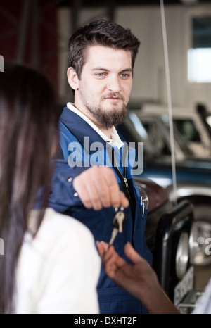 Schöne Auto Mecanic die Schlüssel an dem Client zurückzugeben Stockfoto