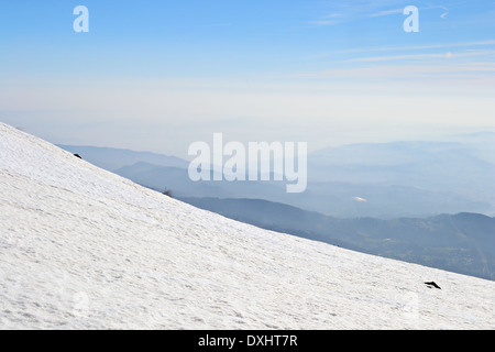 Unendlicher Blick vom einen verschneiten Hang im Frühjahr mit nebligen Hügeln unten. Italienischen Alpen. Stockfoto