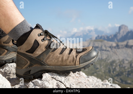 Wanderschuhe von einem Wanderer auf einem Felsen mit Berge Landschaft im Hintergrund Stockfoto