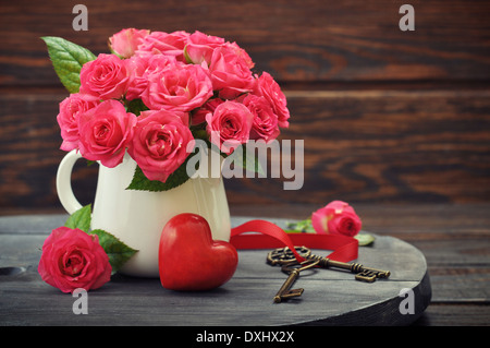 Rose Bouquet mit Stein in Form von Herz und Schlüssel auf hölzernen Hintergrund. Stockfoto