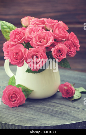 Bouquet von rosa Rosen in Vase auf hölzernen Hintergrund Stockfoto