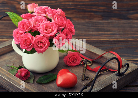 Rose Bouquet mit Stein in Form von Herz und Schlüssel auf hölzernen Hintergrund. Stockfoto