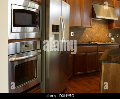 Nahaufnahme Foto von einem Edelstahlgeräte in moderne Wohnküche mit steinernen Gegenoberseiten und Kirsche Holz Schränke Stockfoto