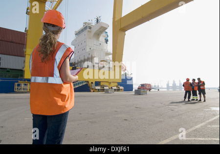 Frau trägt Schutzhelm Dockside Zwischenablage stehen festhalten Stockfoto