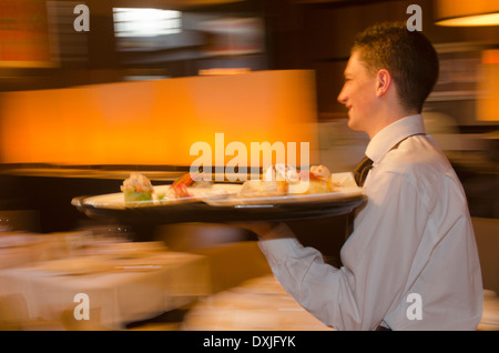 Kellner mit Tablett mit Geschirr über Restaurant Stockfoto