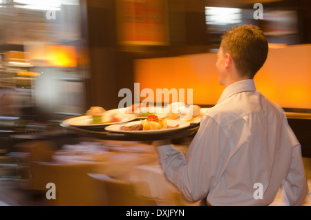 Kellner mit Tablett mit Geschirr über Restaurant Stockfoto