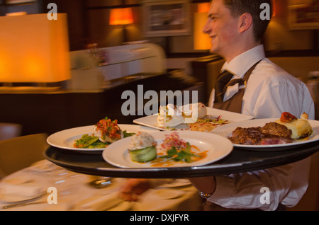 Kellner mit Tablett mit Geschirr über Restaurant Stockfoto