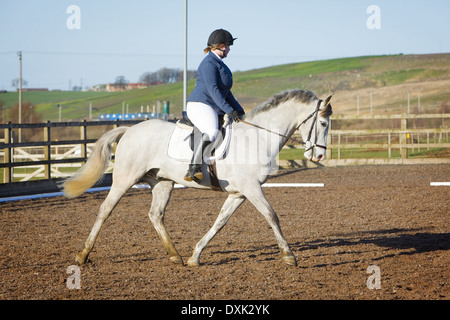 Ein Pferd und Reiter im Wettbewerb in einer Dressur-Veranstaltung außerhalb auf einem Sand und Kurs in England Stockfoto