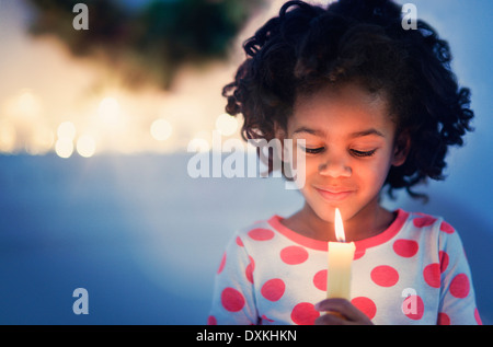 Afroamerikanische Mädchen im Schlafanzug halten zündete eine Kerze an Stockfoto