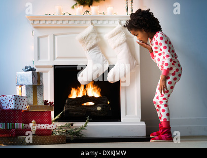 Überrascht, schwarzes Mädchen im Schlafanzug blickte auf Weihnachtsgeschenke Stockfoto