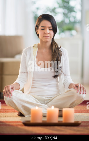 Heitere Hispanic Frau meditieren in der Nähe von brennenden Kerzen Stockfoto