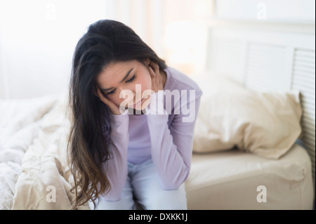 Traurige Hispanic Frau sitzt am Bettrand Stockfoto