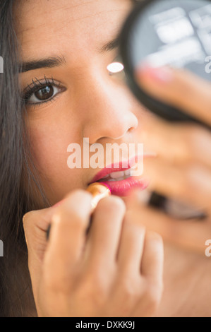 Close up Portrait of Hispanic Frau Auftragen von Lippenstift in Kompakt-Spiegel Stockfoto